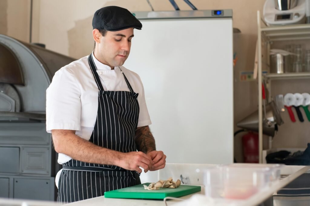 A chef in traditional attire prepares food in a kitchen setting, showcasing culinary skills.